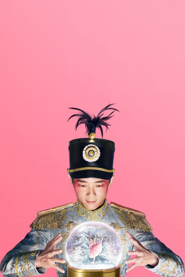 An elaborately dressed man watches a ballerina inside a snow globe.